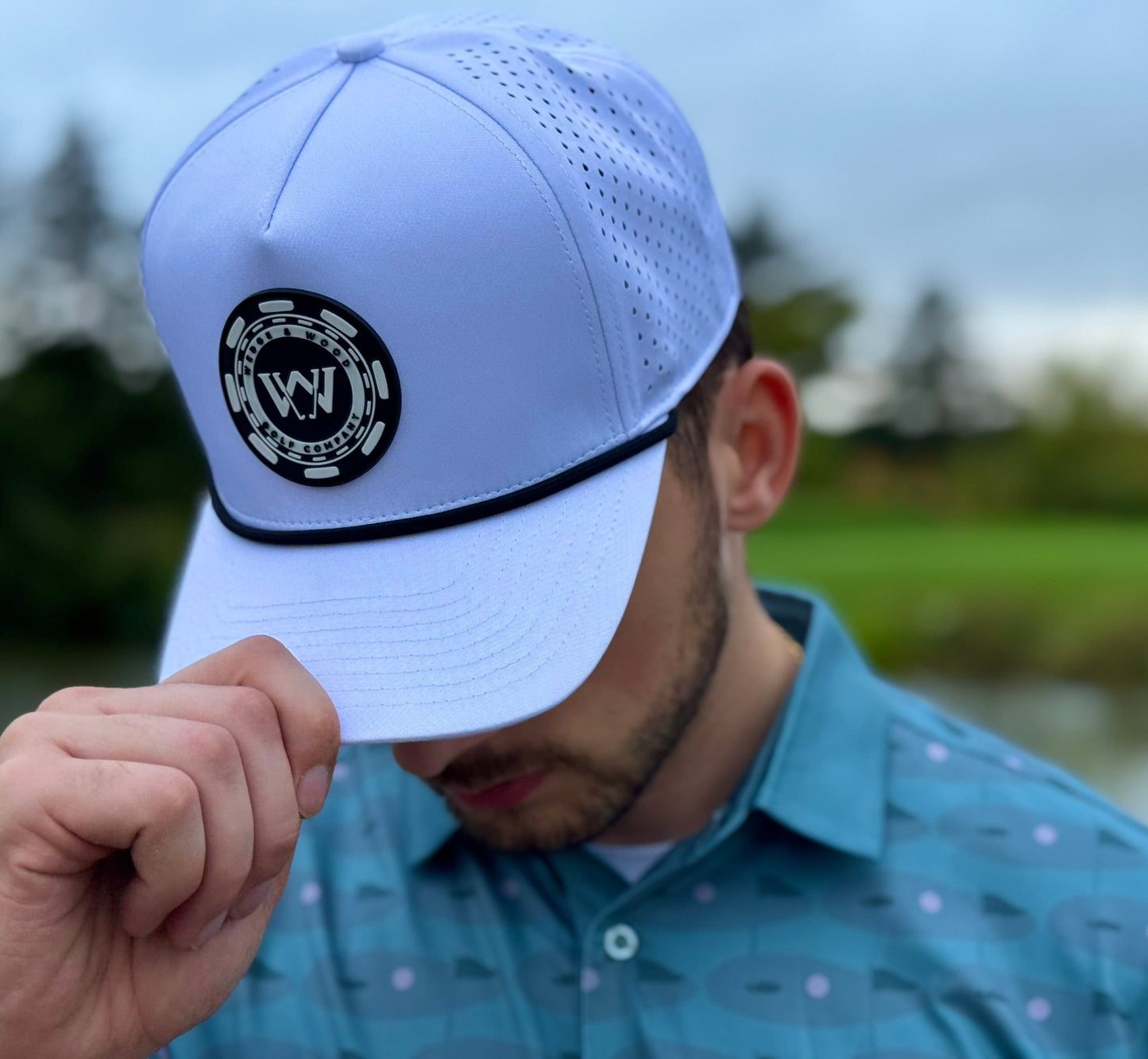 Man wearing Wedge and Wood Greens logo polo shirt with white poker chip logo performance golf hat