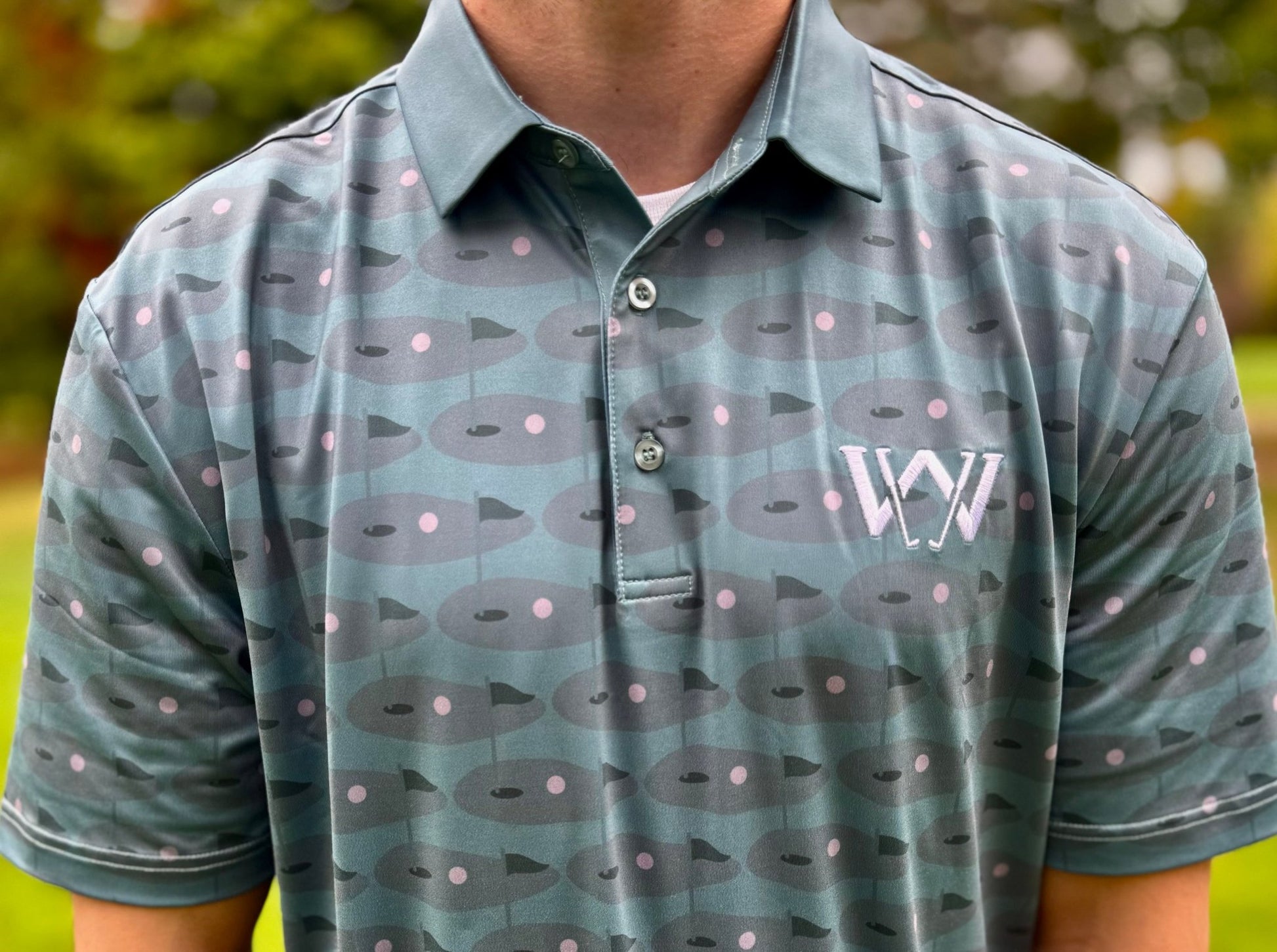 Close up of material and pattern of Wedge and Wood Greens logo polo shirt