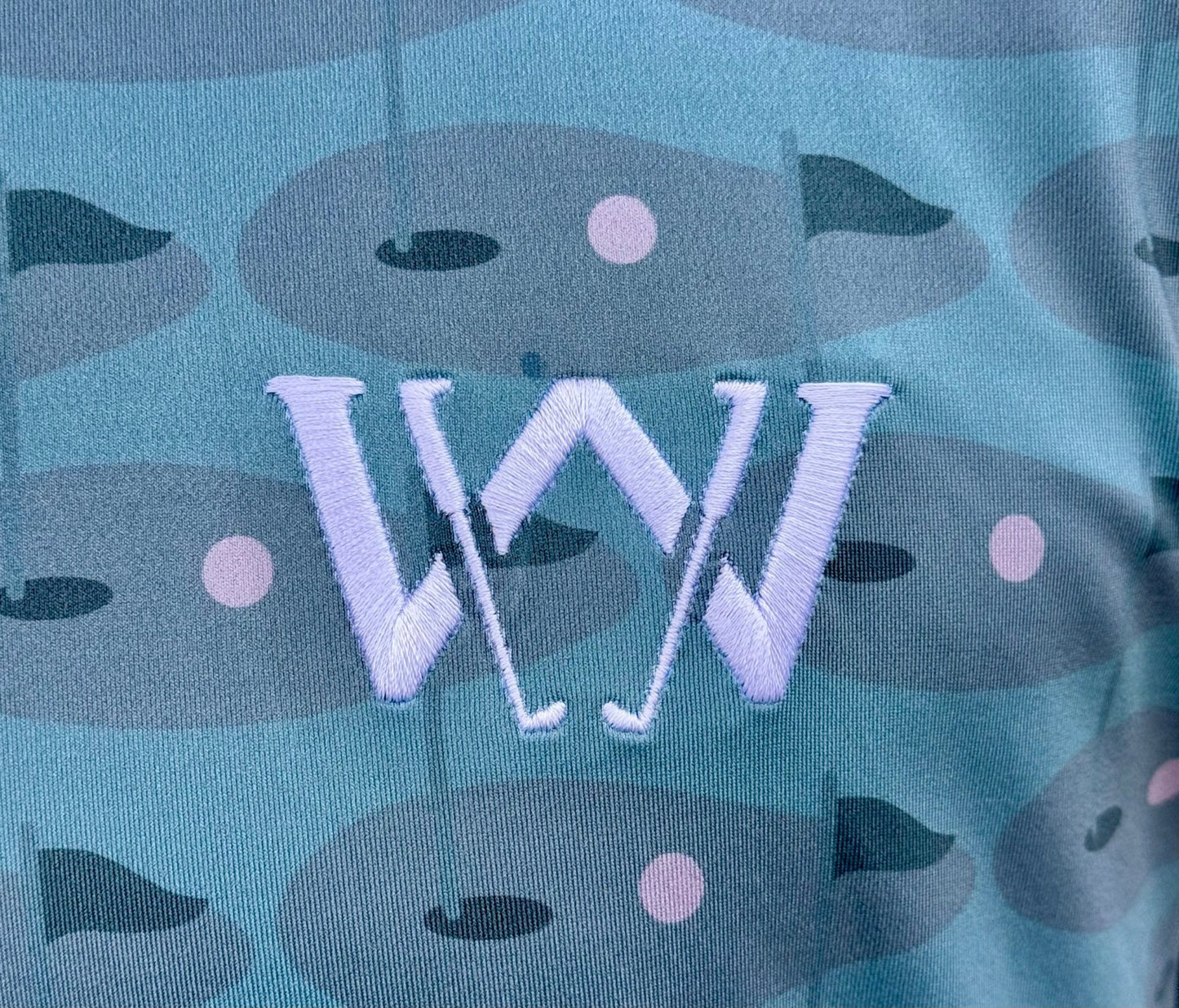 Close up of stitched logo on wedge and wood greens golf polo shirt