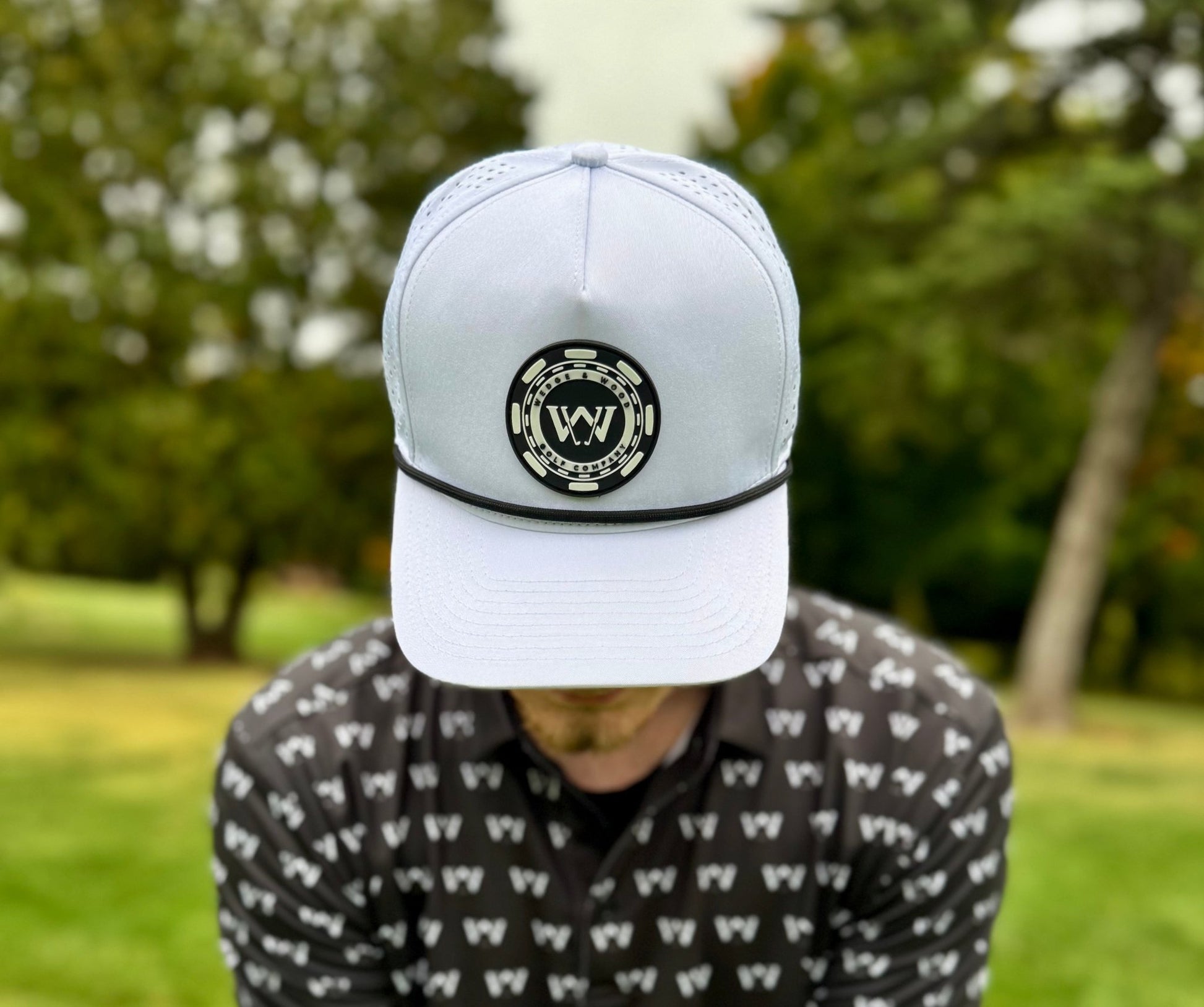 Man wearing black OG logo golf polo shirt with white poker logo performance hat