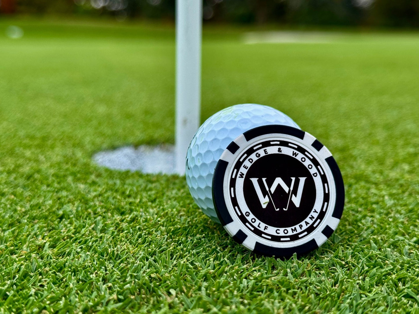 Poker chip ball marker leaned up against ball on golf green