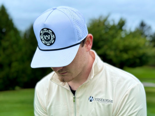Man wearing tan q-zip and white wedge and wood poker chip logo performance golf hat