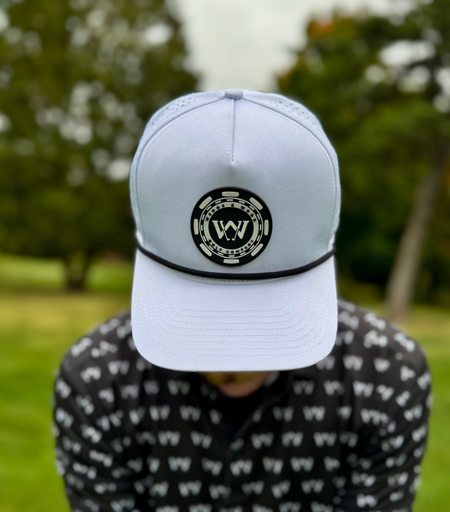 Man wearing white poker chip logo golf hat with Wedge and Wood OG logo polo shirt on golf course